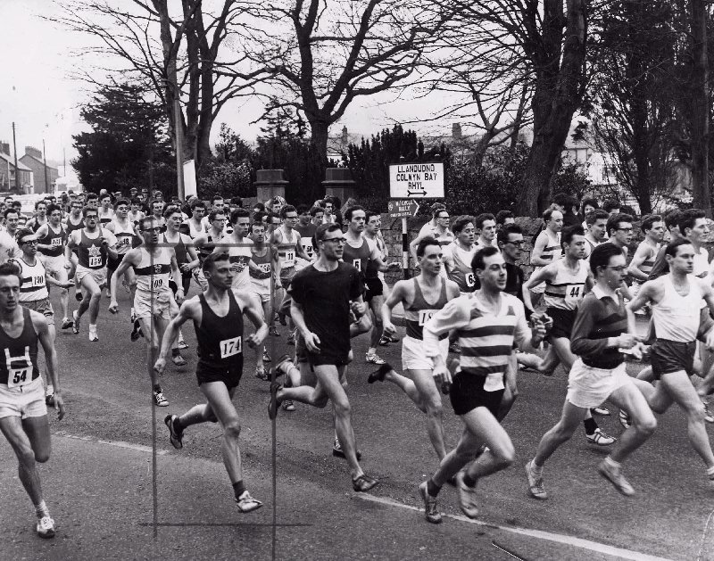 Competitors (including Brian Woolford) in the St. Asaph to Rhyl road race on Saturday jostle for positions at the mass start outside the Old Deanery, St. Asaph. The event is now the biggest road race in Wales, and attracts record numbers of runners. The winner was Ron Hill of Bolton.