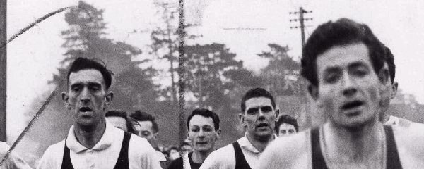 Brian Craig and Ron Barlow jostle for first position soon after the start of the St. Asaph to Rhyl road race organized annually by the Rhyl Athletic Club. Craig number 1 is from Blackpool and Barlow number 184 is from Wallasey A.C.